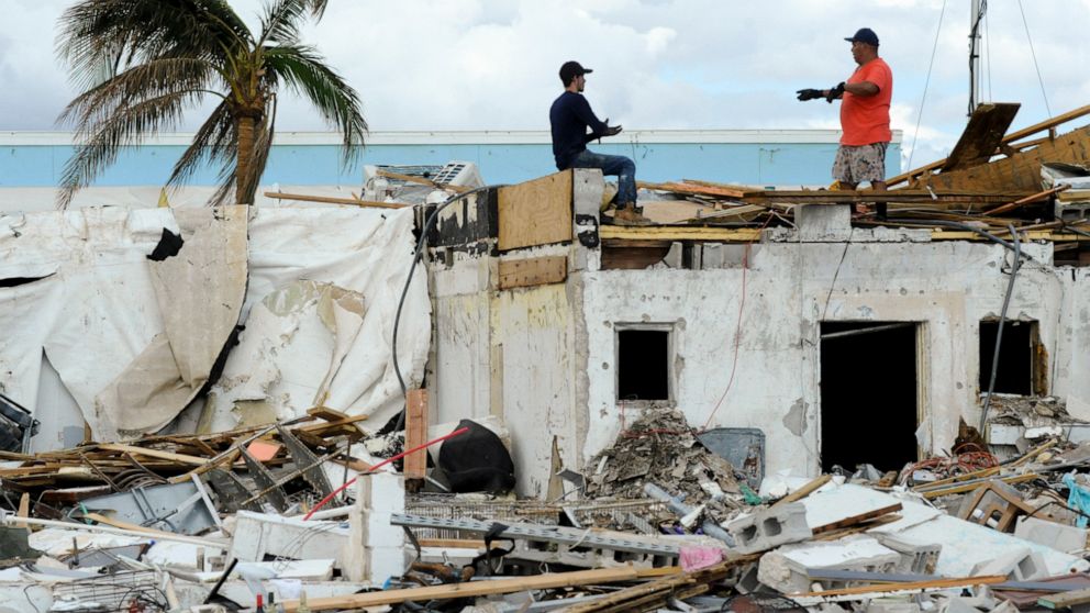 Workers talk atop a building that was heavily damaged by Hurricane Ian at Fort Myers Beach, Fla., on Sunday, Oct. 9, 2022. (AP Photo/Jay Reeves)