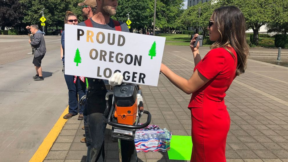 A TV reporter interviews self-employed logger Bridger Hasbrouck, of Dallas, Ore., outside the Oregon State House in Salem, Ore., on Thursday, June 20, 2019, the day the Senate is scheduled to take up a bill that would create the nation's second cap-a