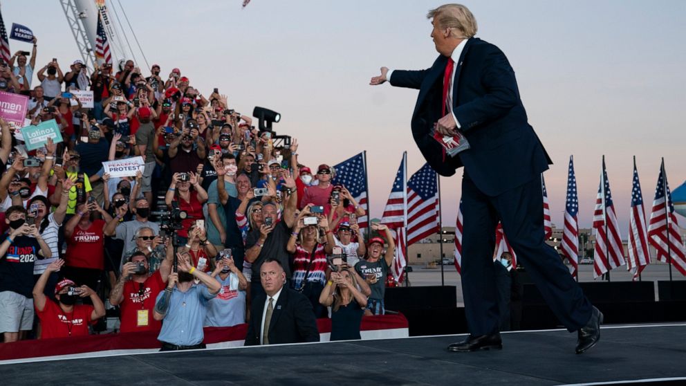 President Donald Trump throws face masks into the crowd as he arrives for a campaign rally at Orlando Sanford International Airport, Monday, Oct. 12, 2020, in Sanford, Fla. (AP Photo/Evan Vucci)