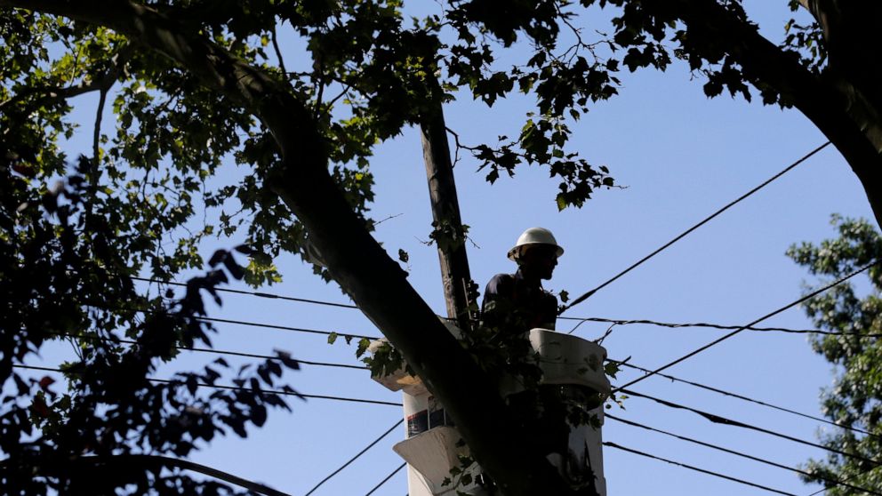 FILE - A utility crew works to restore power to houses in the Woodhaven section of the Queens borough of New York, following a storm, Tuesday, Aug. 11, 2020. At least 1.4 million households and other residential customers are behind on electric and g