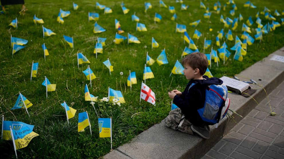 A boy watches flags honoring soldiers killed fighting Russian troops in downtown Kyiv, Ukraine, Monday, May 23, 2022. (AP Photo/Natacha Pisarenko)