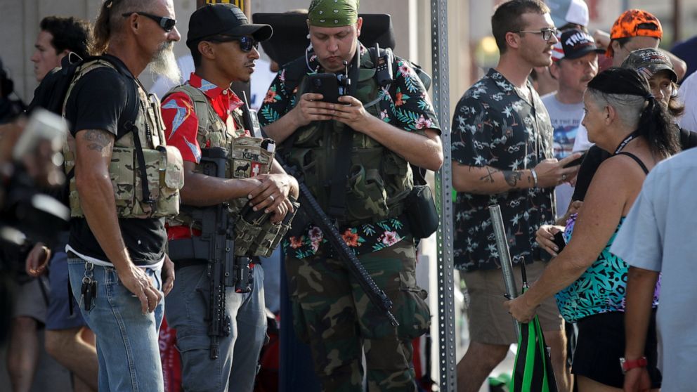 FILE - In this June 20, 2020 file photo, gun-carrying men wearing Hawaiian print shirts associated with the boogaloo movement watch a demonstration near where President Trump had a campaign rally in Tulsa, Okla. People following the anti-government b