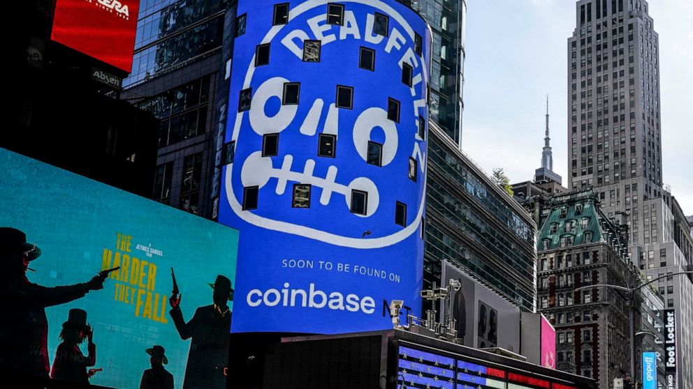 FILE - An advertisement for Coinbase, center, is displayed on NASDAQ billboard in Times Square, New York, Thursday, Nov. 4, 2021. New York announced a $100 million settlement with Coinbase on Wednesday over what state officials called significant fai