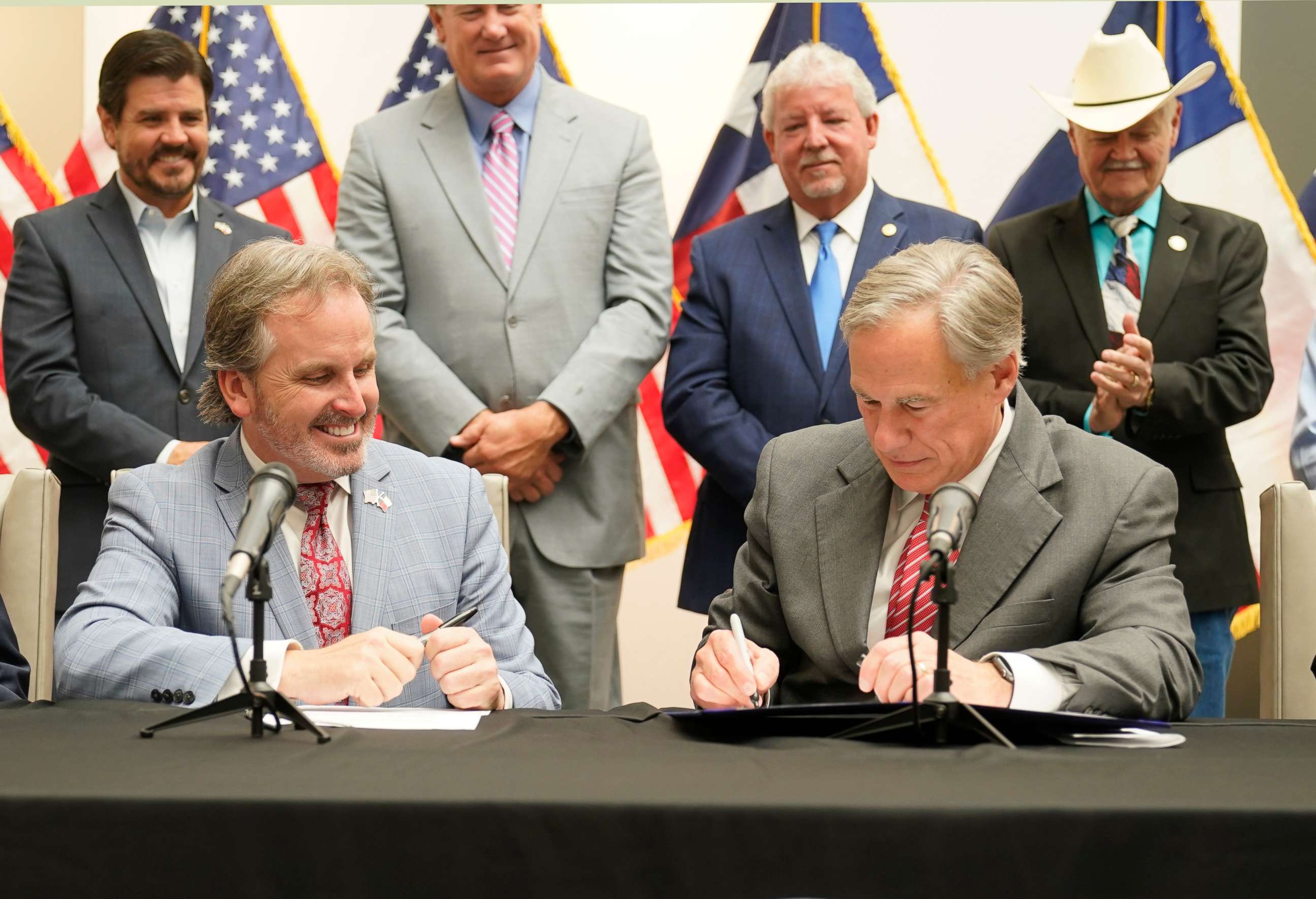PHOTO: Texas Gov. Greg Abbott signs Senate Bill 1, also known as the election integrity bill, into law with State Sen. Bryan Hughes looking on with others in the background in Tyler, Texas, on Sept. 7, 2021. 