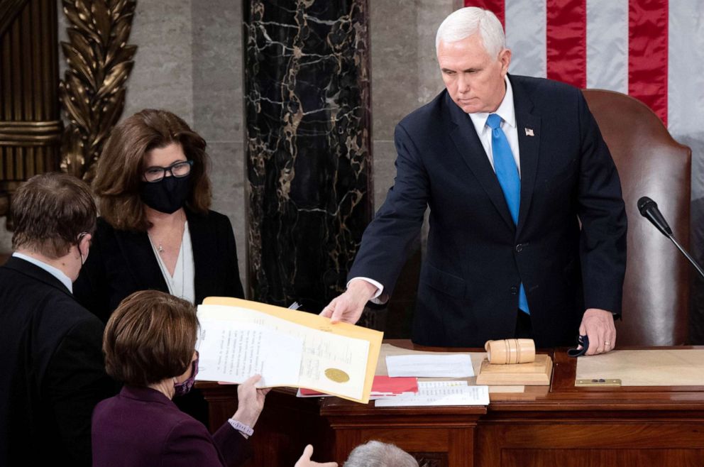 PHOTO: Vice President Mike Pence hands the electoral certificate from the state of Arizona to Sen. Amy Klobuchar, as he presides over a joint session of Congress to certify the 2020 election results on Capitol Hill  Jan. 6, 2021. 