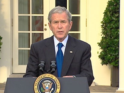 A picture of President Bush speaking in front of the White House.