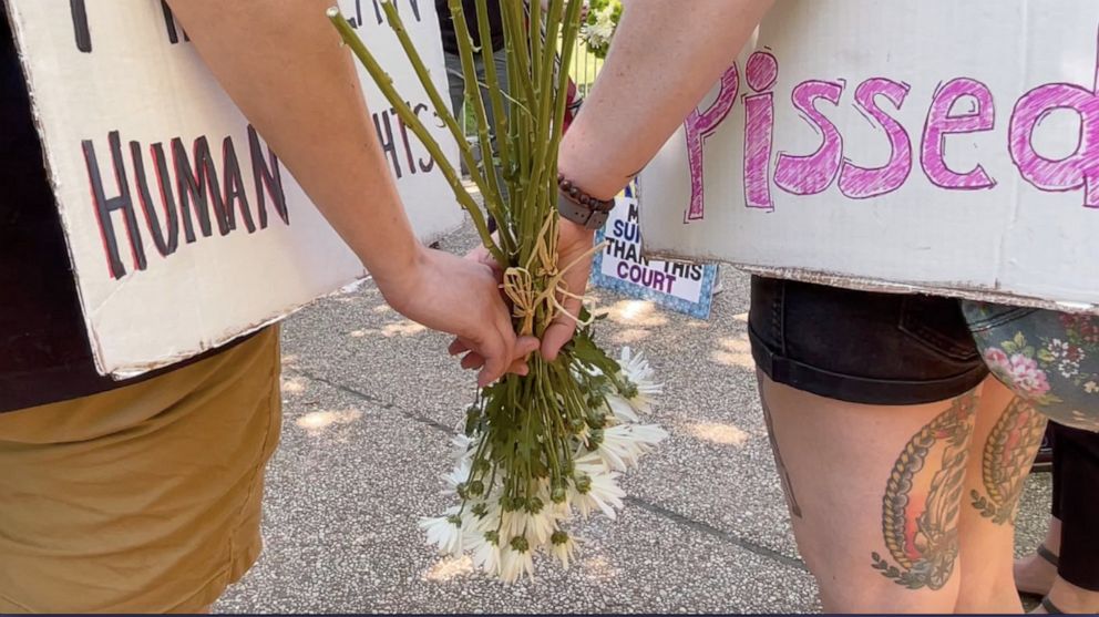 PHOTO: Abortion suporters hold flowers and signs protesting outside the Supreme Court in Washington, D.C., on July 11, 2022.
