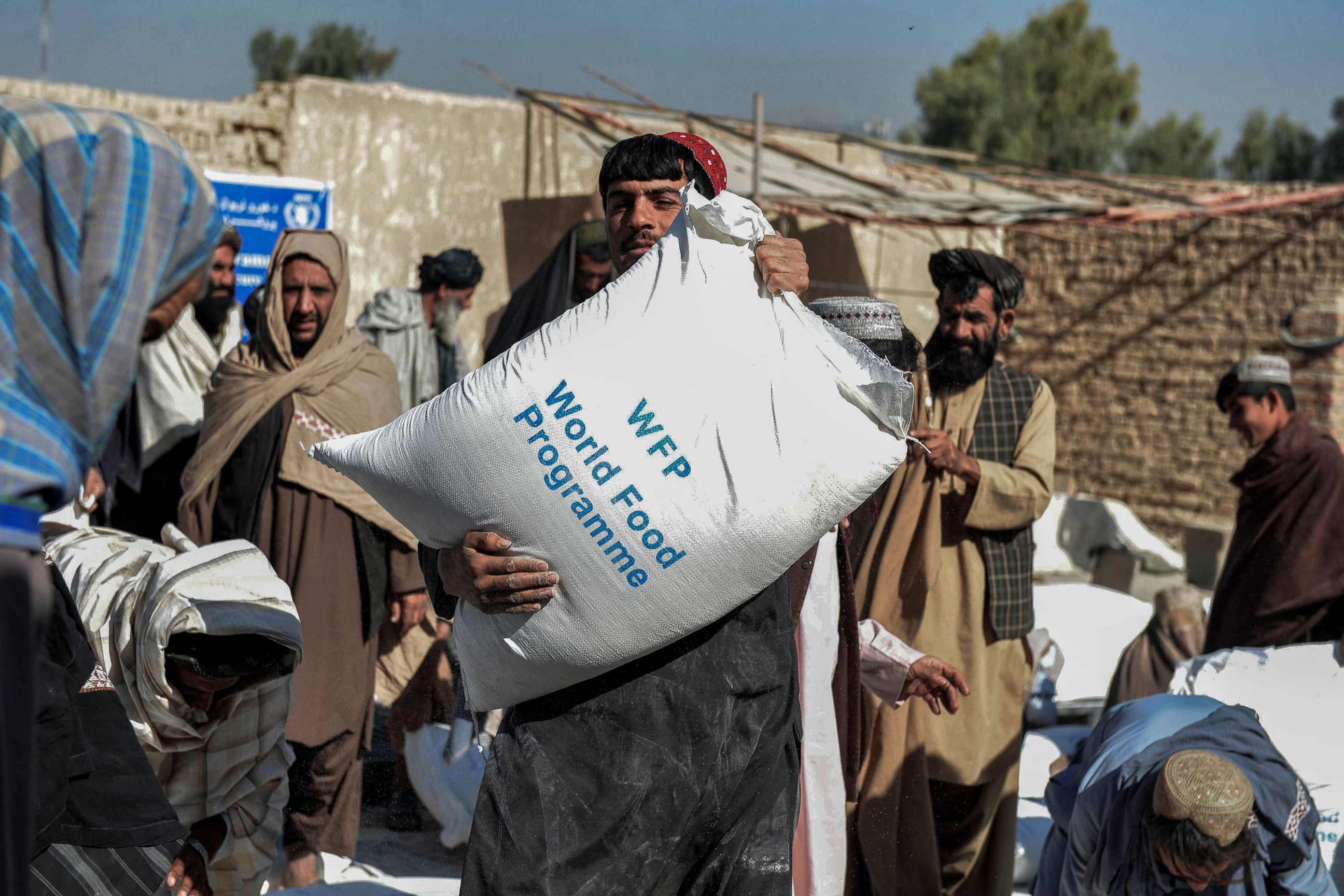 PHOTO: Afghans carry sacks of grain distributed as aid by the World Food Programme in Kandahar, Afghanistan, Oct, 19, 2021. 