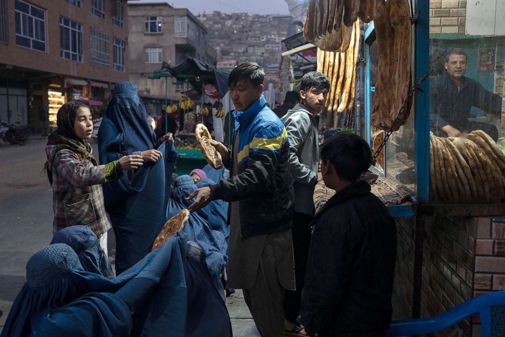 PHOTO: A man distributes bread to Afghan women outside a bakery in Kabul, Afghanistan, Dec, 2, 2021. 