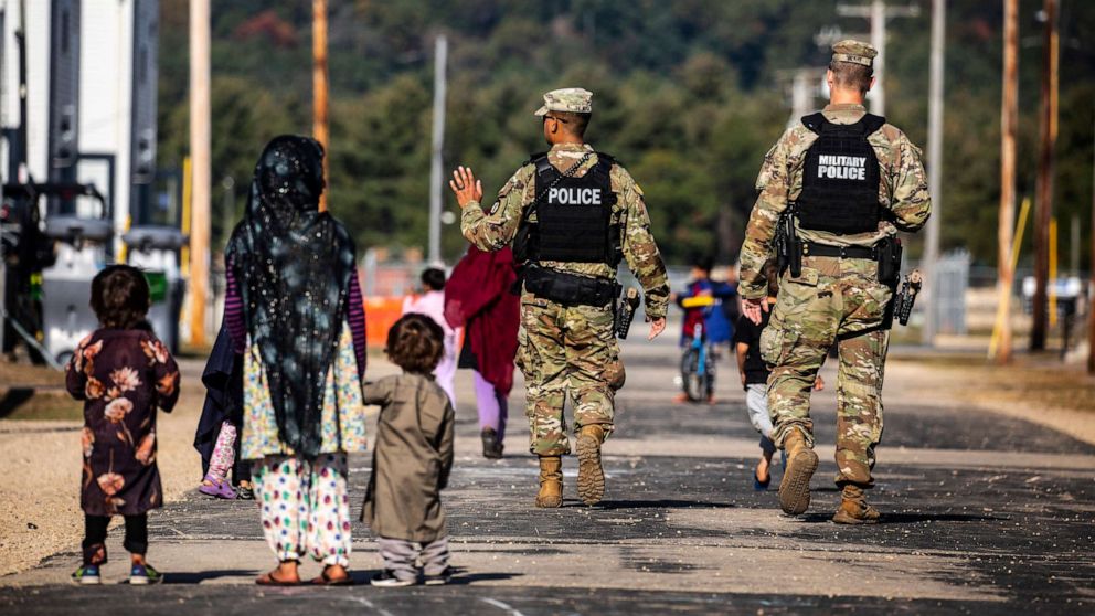 PHOTO: U.S. Military Police walk past Afghan refugees at the Village at the Ft. McCoy U.S. Army base on Sept. 30, 2021 in Ft. McCoy, Wis.