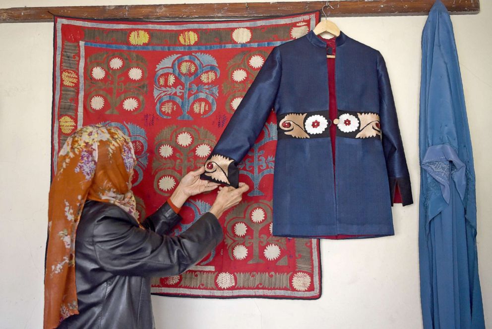 PHOTO: An Afghan tailor hangs a coat embroidered with traditional textiles and motives, on the wall of a store in Kabul, Feb. 25, 2018.