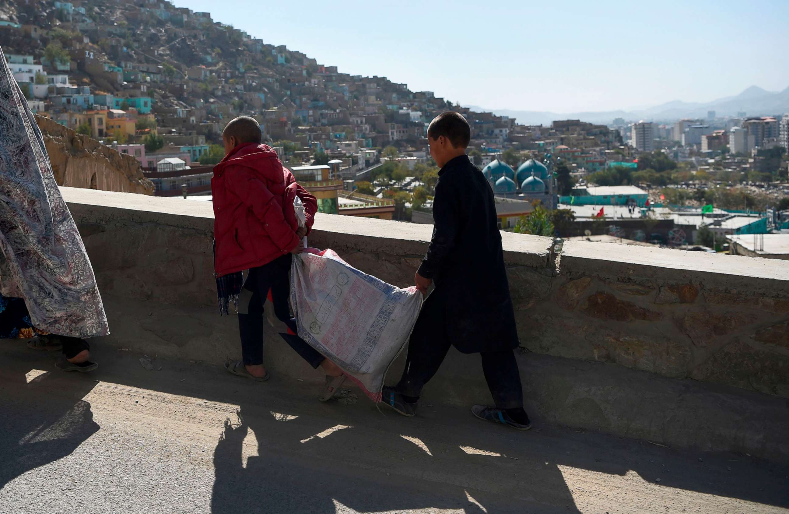 PHOTO: Boys carry a sack along a road overlooking Kabul, Afghanistan, Oct. 25, 2020. 