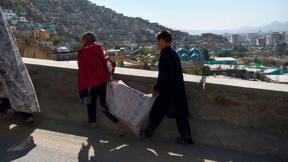 PHOTO: Boys carry a sack along a road overlooking Kabul, Afghanistan, Oct. 25, 2020. 