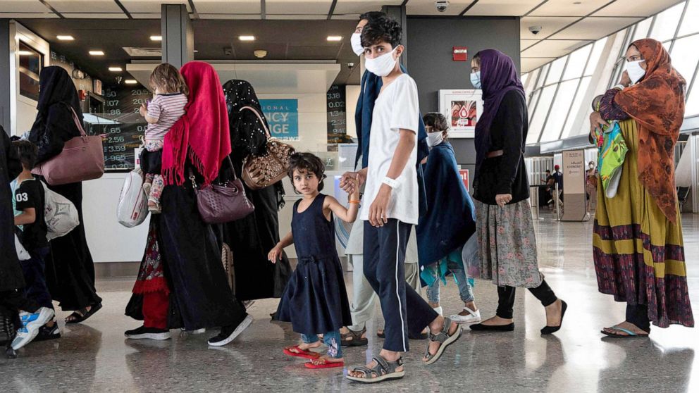 PHOTO: Refugees from Afghanistan are escorted to a waiting bus after arriving and being processed at Dulles International Airport in Dulles, Va., Aug. 23, 2021.
