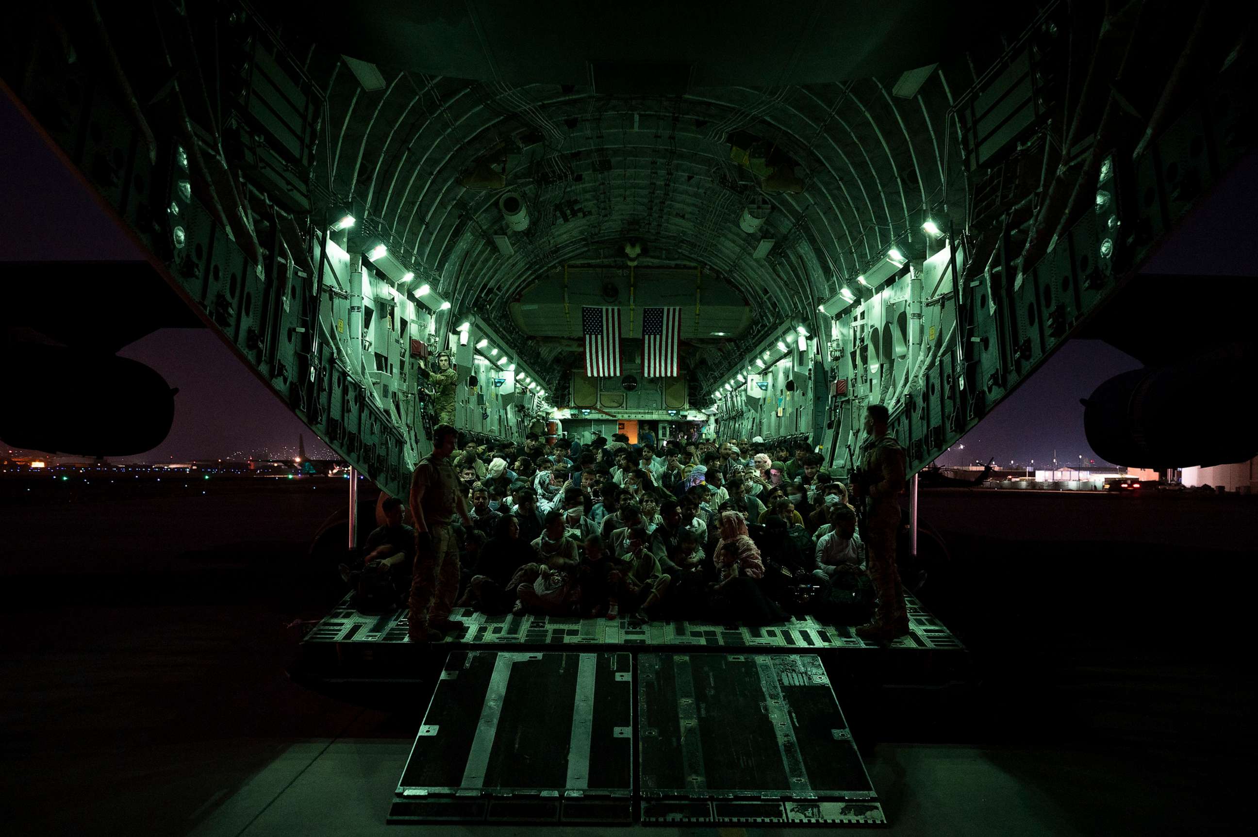PHOTO: An air crew assigned to the 816th Expeditionary Airlift Squadron assists evacuees aboard a C-17 Globemaster III aircraft in support of the Afghanistan evacuation at Hamid Karzai International Airport, August 21, 2021, in Kabul, Afghanistan.