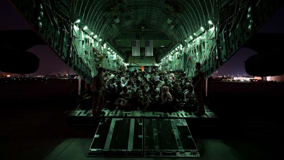 PHOTO: An air crew assigned to the 816th Expeditionary Airlift Squadron assists evacuees aboard a C-17 Globemaster III aircraft in support of the Afghanistan evacuation at Hamid Karzai International Airport, August 21, 2021, in Kabul, Afghanistan.