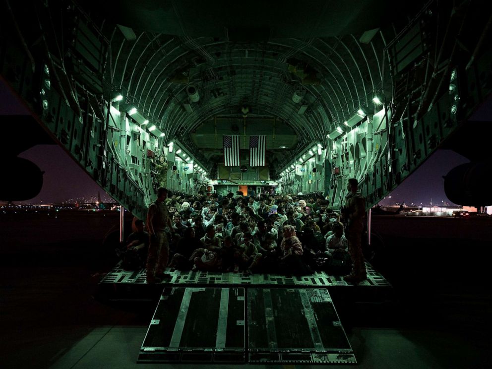 PHOTO: An air crew assigned to the 816th Expeditionary Airlift Squadron assists evacuees aboard a C-17 Globemaster III aircraft in support of the Afghanistan evacuation at Hamid Karzai International Airport, August 21, 2021, in Kabul, Afghanistan.