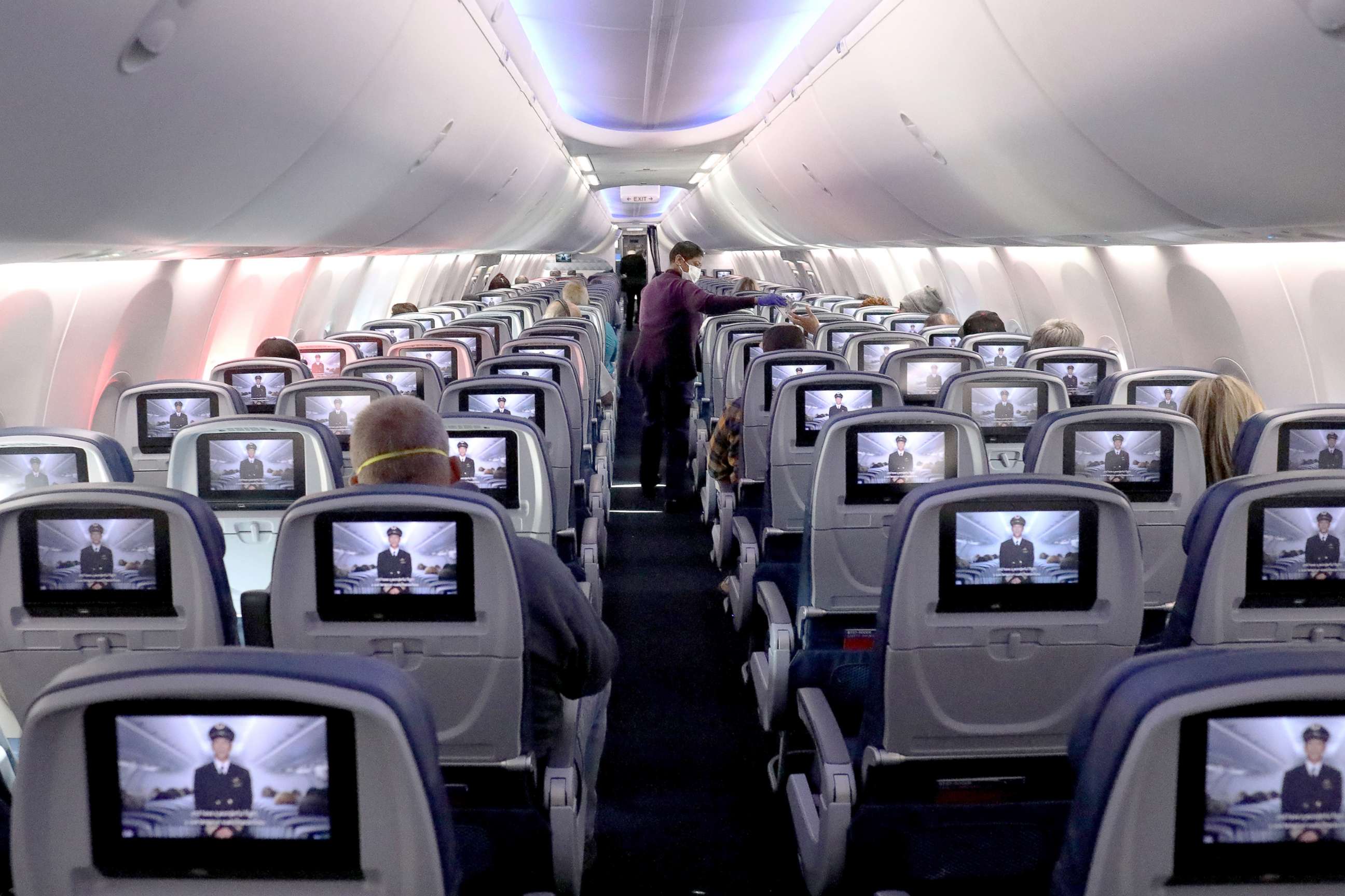 PHOTO: A flight attendant hands out headphones on a Delta flight departing from Hartsfield-Jackson Atlanta International Airport on April 20, 2020.