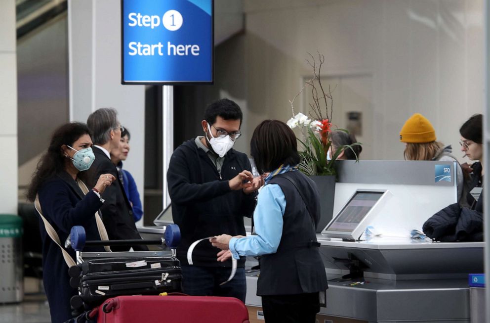 PHOTO: Passengers wear protective masks as they check into an international flight at San Francisco International Airport on March 06, 2020.
