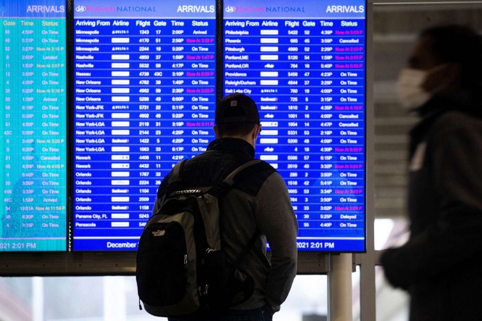 PHOTO: A person looks at a flight status board at Ronald Reagan Washington National Airport in Arlington, Va., Dec. 27, 2021.