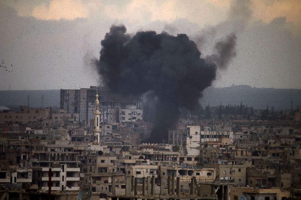   PHOTO: Smoke Escapes Buildings as a Result of a Ground-to-Ground Missile Firing in an Area held by Rebels in Daraa City, Southern Syria, on 23 March 2018. 