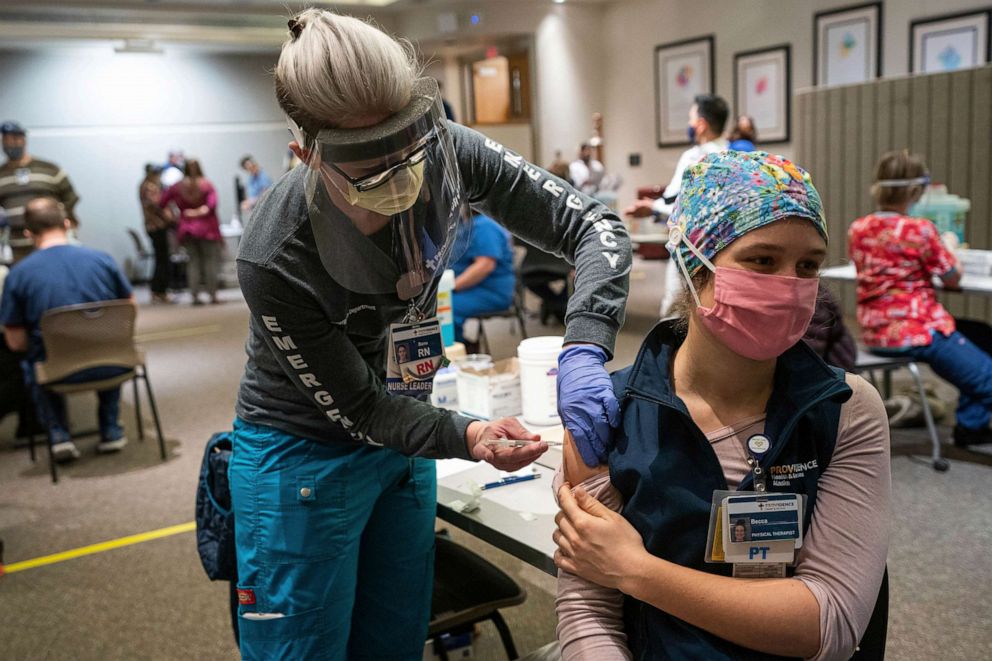 PHOTO: Registered Nurse Banu Mufale administers a Pfizer-BioNtech COVID-19 vaccine to physical therapist Becca Mamrol, Dec. 16, 2020, at Providence Alaska Medical Center in Anchorage, Alaska.