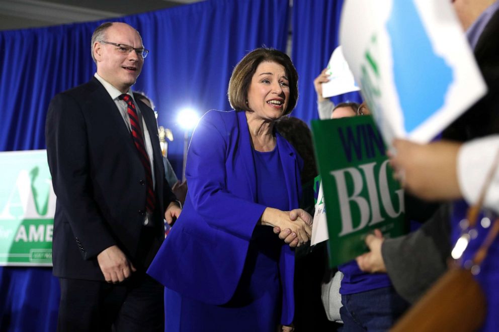 PHOTO: Sen. Amy Klobuchar (D-MN) takes the stage with her husband John Bessler as a Democratic president candidate during a primary night event at the Grappone Conference Center in Concord, New Hampshire, on Feb. 11, 2020. 