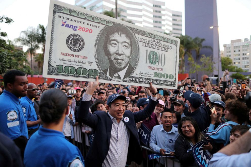 PHOTO: Democratic presidential candidate Andrew Yang hoists a supporter's sign after speaking at a rally in downtown Los Angeles, April 22, 2019.