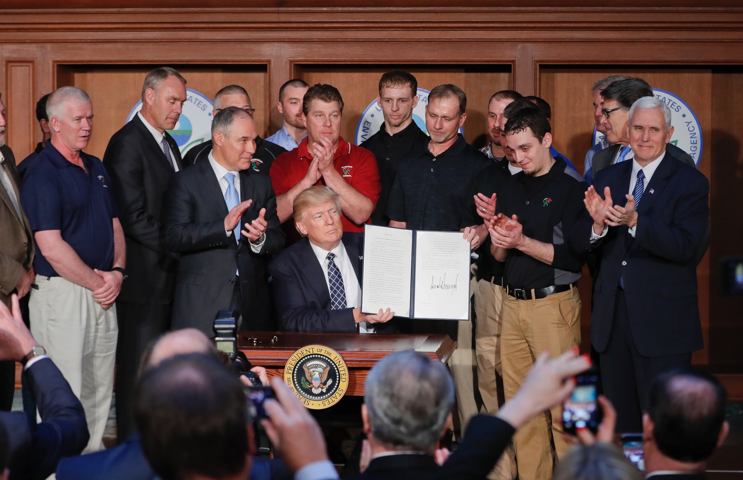 PHOTO: President Donald Trump, accompanied by Environmental Protection Agency (EPA) Administrator Scott Pruitt, third from left, applaud as he holds up the signed Energy Independence Executive Order, March 28, 2017, at EPA headquarters in Washington.