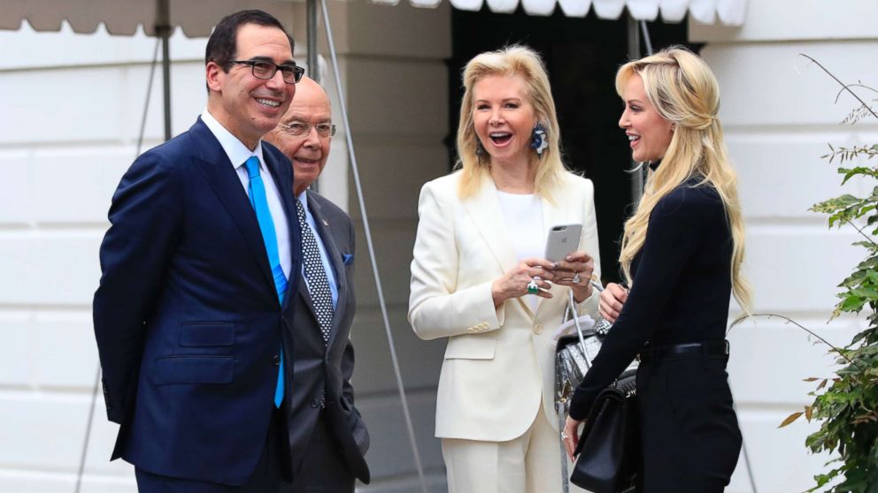 PHOTO: Treasury Secretary Steven Mnuchin, left, and his wife, Louise Linton, right, and Secretary of Commerce Wilbur Ross, second from left, and his wife Hilary Geary, second from right, wait for President Trump at the White House, July 29, 2017. 