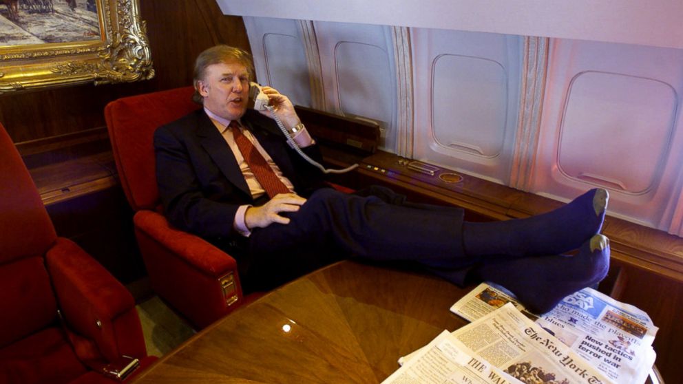 Donald Trump uses the phone and puts his sock-covered feet on the table in his private plane as he flies to Minnesota for a speech and to attend a fund-raiser for Gov. Jesse Ventura, Friday Jan. 7, 2000.