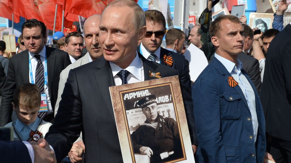 PHOTO: Russian President Vladimir Putin holds a photograph of his father in his naval uniform as he shakes hands with people during the the commemoration of the 70th anniversary of victory over Nazi Germany, Moscow, Russia, May 9, 2015. 