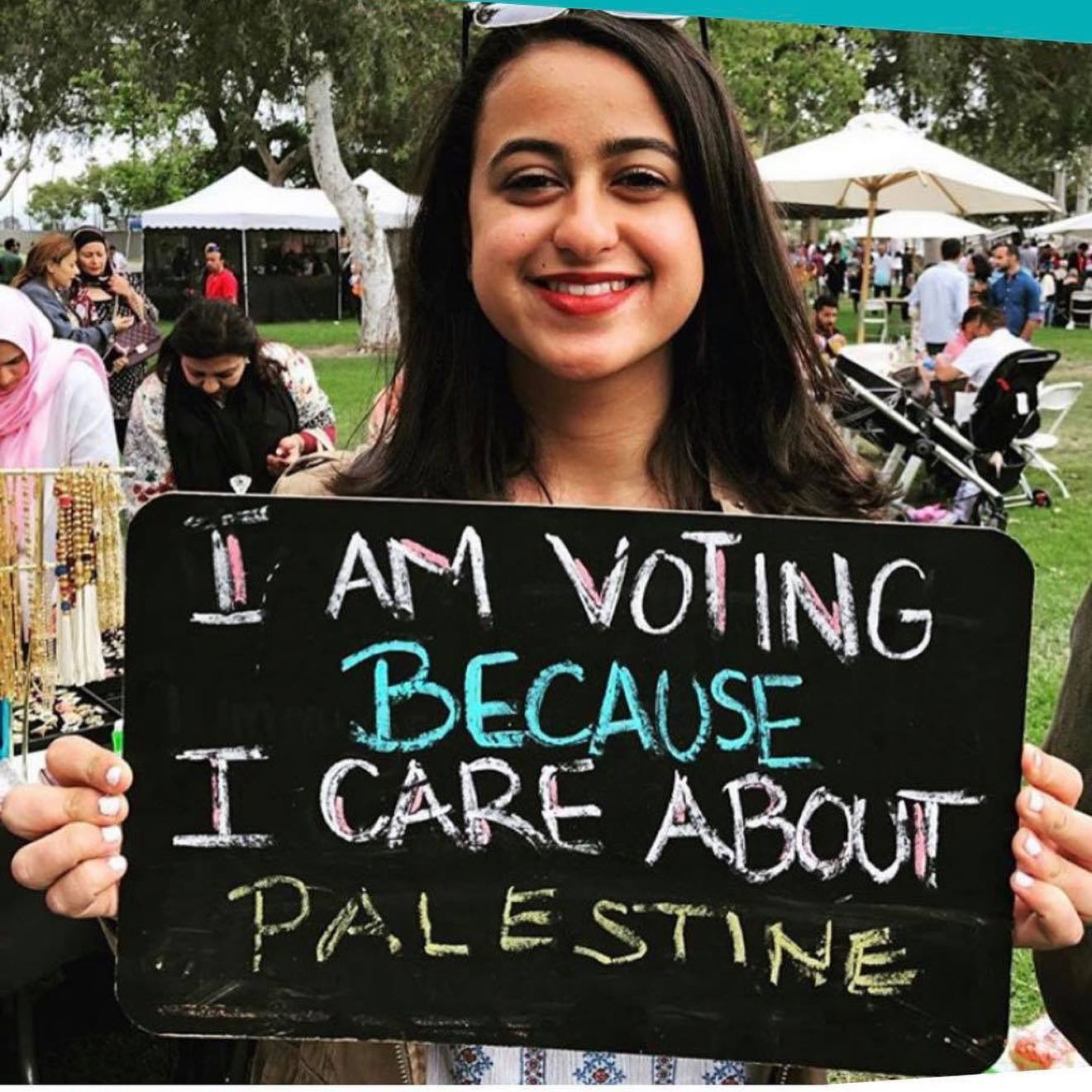 PHOTO: A voter holds a chalkboard on National Arab American voter registration day to show why she is casting her vote this year, in Calif.