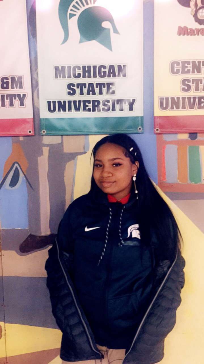 PHOTO: High School senior Arieyanna Williams stands in front a Michigan State flag as the college she's committed to in a hall at her elementary school in Chicago, Illinois. 