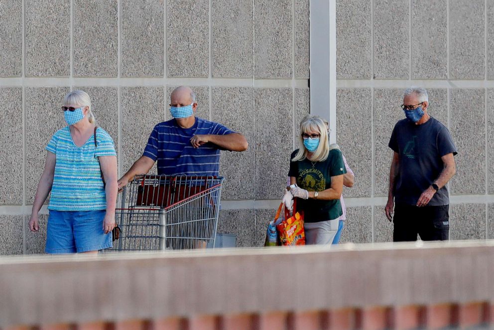 PHOTO: Customers wear masks as they wait to enter a store June 17, 2020, in Tempe, Ariz.