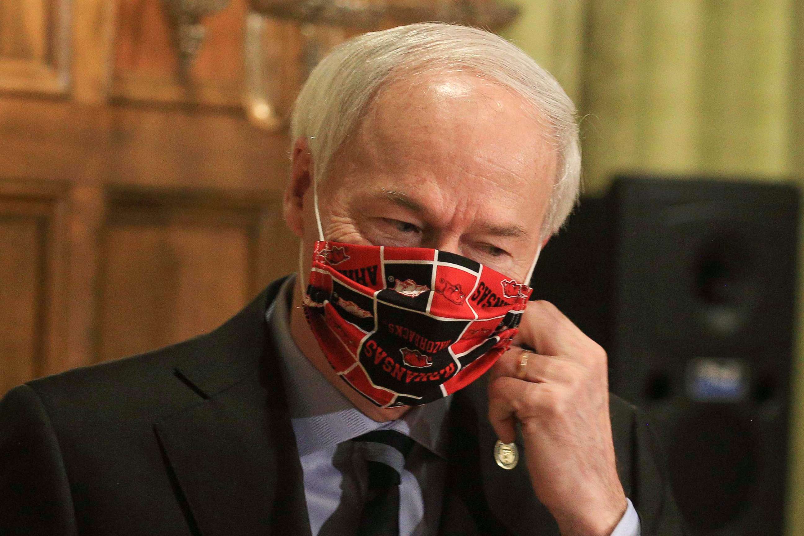 PHOTO: Gov. Asa Hutchinson takes off his Arkansas Razorbacks facemark as he arrives for the daily coronavirus briefing at the state Capitol in Little Rock, April 27, 2020. 