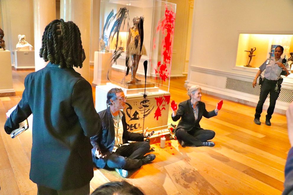 PHOTO: Declare Emergency protesters sit on the floor after smearing paint on the case and pedestal of Edgar Degas's "Little Dancer Aged Fourteen" sculpture in the National Gallery of Art in Washington, Apr, 27, 2023.