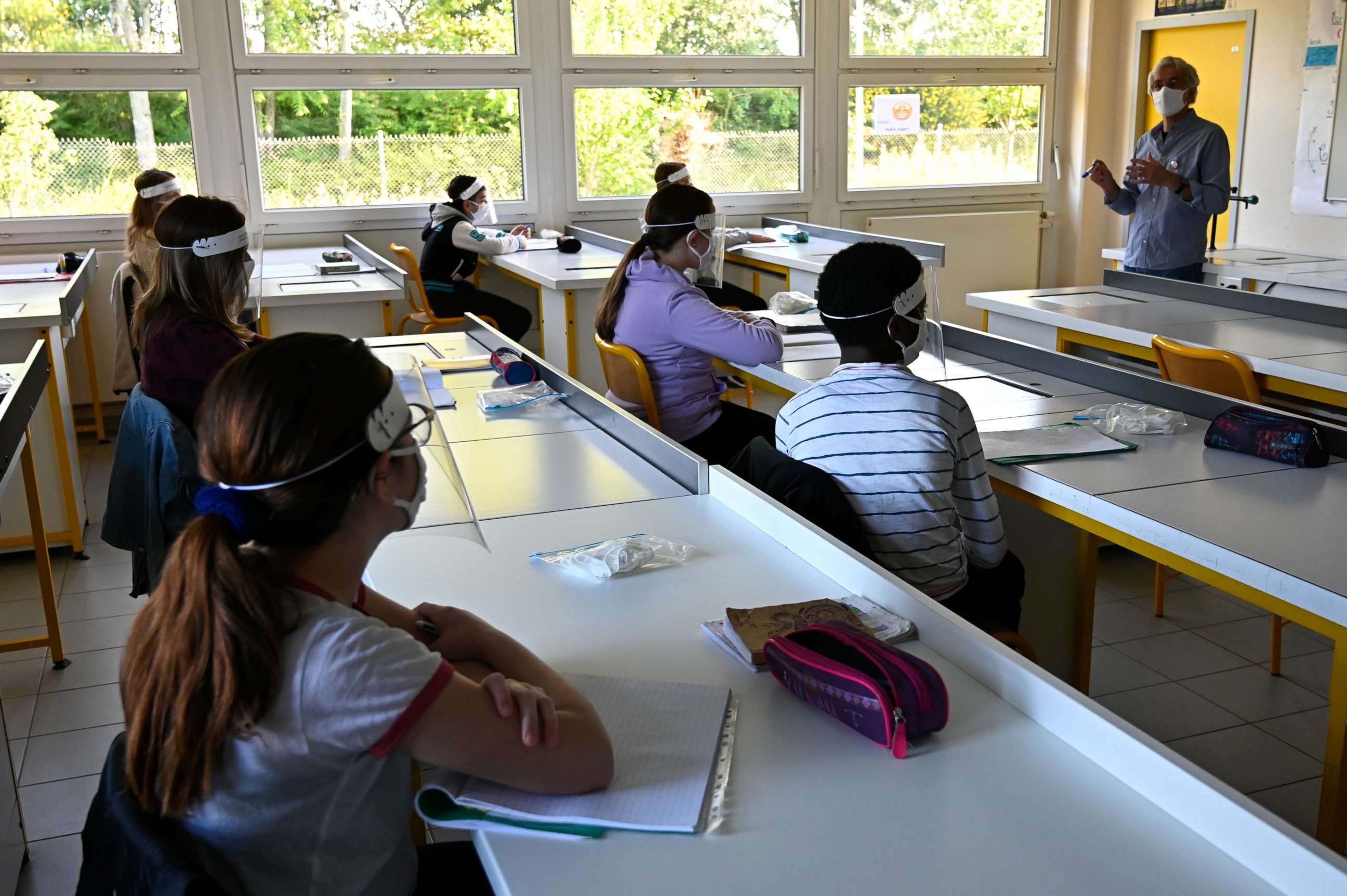 PHOTO: Schoolchildren wearing protective mouth masks and face shields listen to their teacher in a classroom at Claude Debussy college in Angers, France, May 18, 2020.