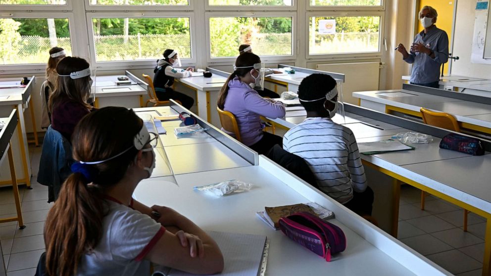 PHOTO: Schoolchildren wearing protective mouth masks and face shields listen to their teacher in a classroom at Claude Debussy college in Angers, France, May 18, 2020.