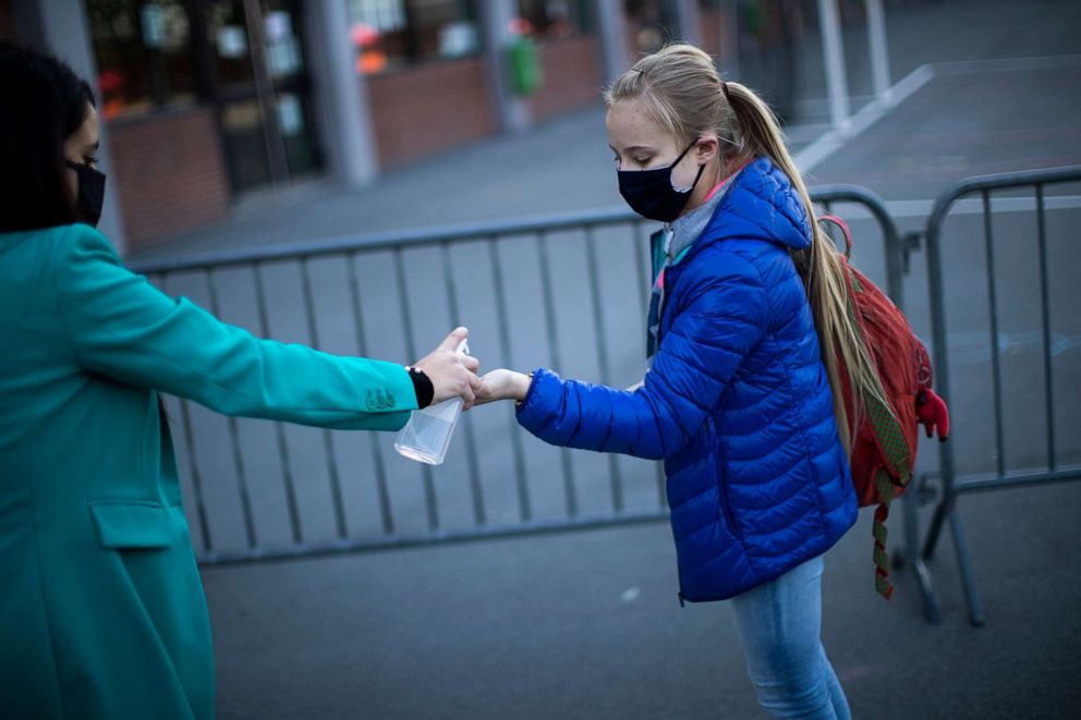 PHOTO: A student wearing a face mask is offered hand gel before entering the classroom at Les Magnolias primary school during the partial lifting of coronavirus, COVID-19, lockdown regulations in Brussels, May 18, 2020.