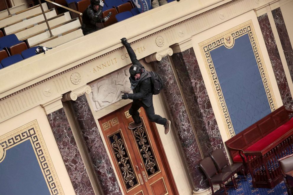 PHOTO: A protester is seen hanging from the balcony in the Senate Chamber, Jan. 6, 2021, in Washington, D.C., as congress held a joint session today to ratify President-elect Joe Biden's 306-232 Electoral College win over President Donald Trump.