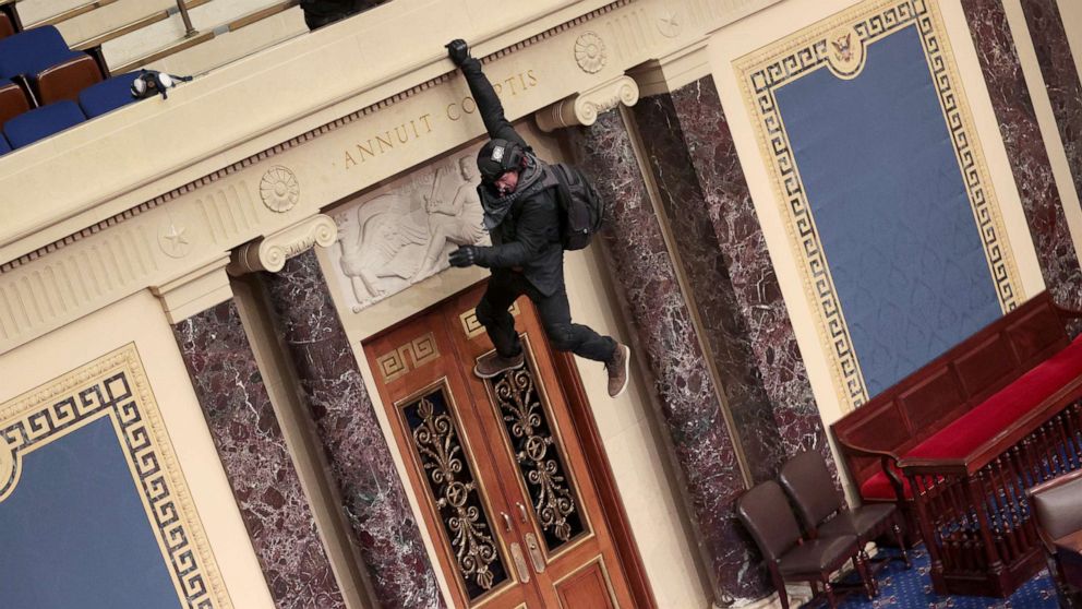 PHOTO: A protester is seen hanging from the balcony in the Senate Chamber, Jan. 6, 2021, in Washington, D.C., as congress held a joint session today to ratify President-elect Joe Biden's 306-232 Electoral College win over President Donald Trump.