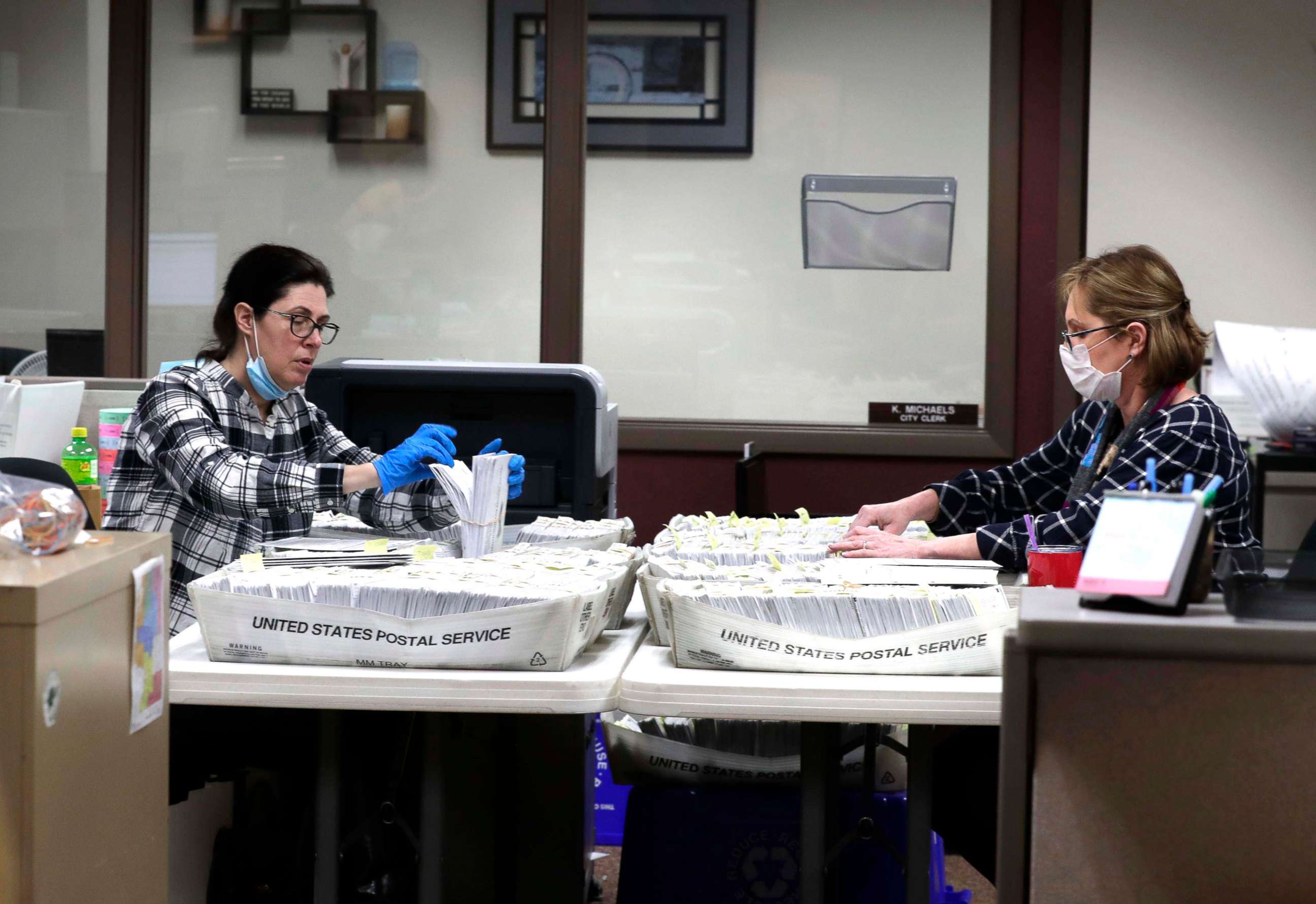 PHOTO: From left Katherine Katsekes, and Diane Scott, both paid volunteers, help sort absentee ballots by ward to be opened on election day at Brookfield City Hall, Tuesday, March 31, 2020.