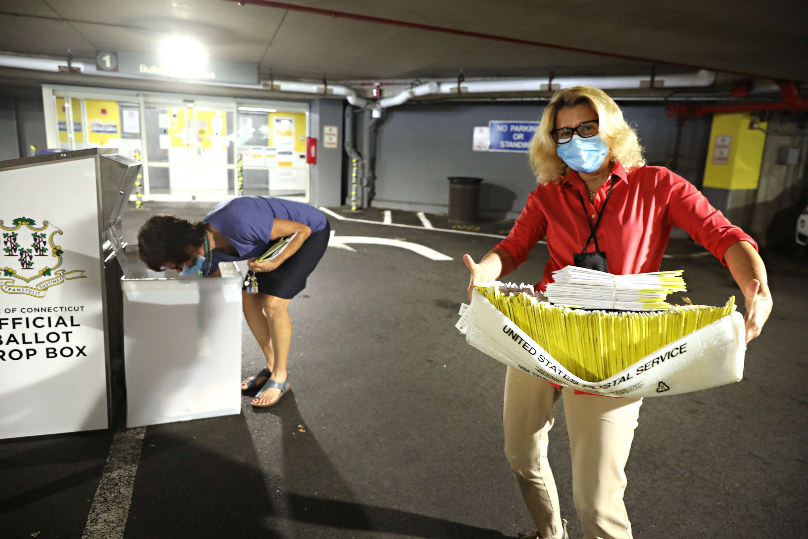 PHOTO: A polling worker carries 2020 presidential primary ballots that were dropped off at a post office and brought to a government center to be processed and counted at the Stamford Government Center on Aug. 11, 2020, in Hartford, Conn.