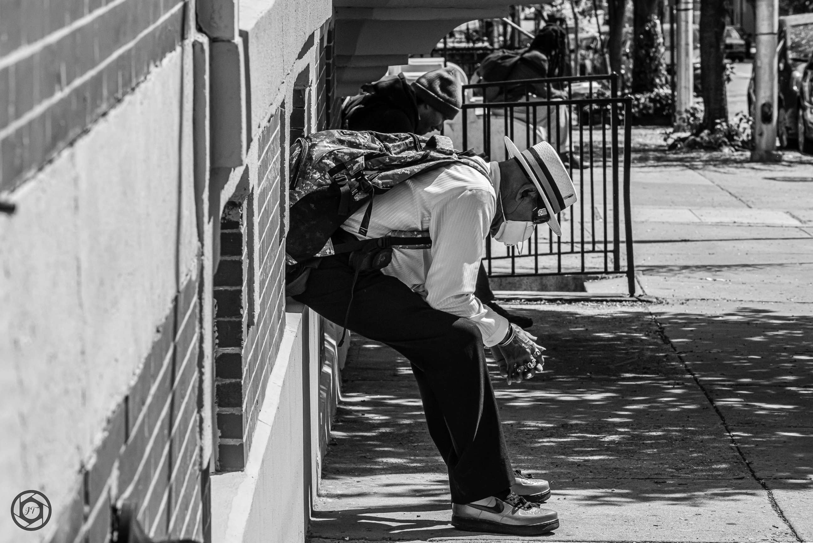 PHOTO:  A masked African American man takes a rest on a downtown Baltimore street during the coronavirus pandemic in May 2020.