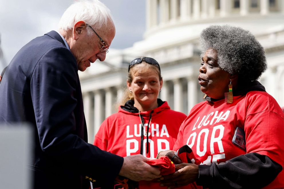 PHOTO: Labor activist "Mama Cookie" Bradley gifts Sen. Bernie Sanders (I-VT) a T-Shirt before a press conference on raising the federal minimum wage outside the Capitol Building, May 04, 2023 in Washington, DC.
