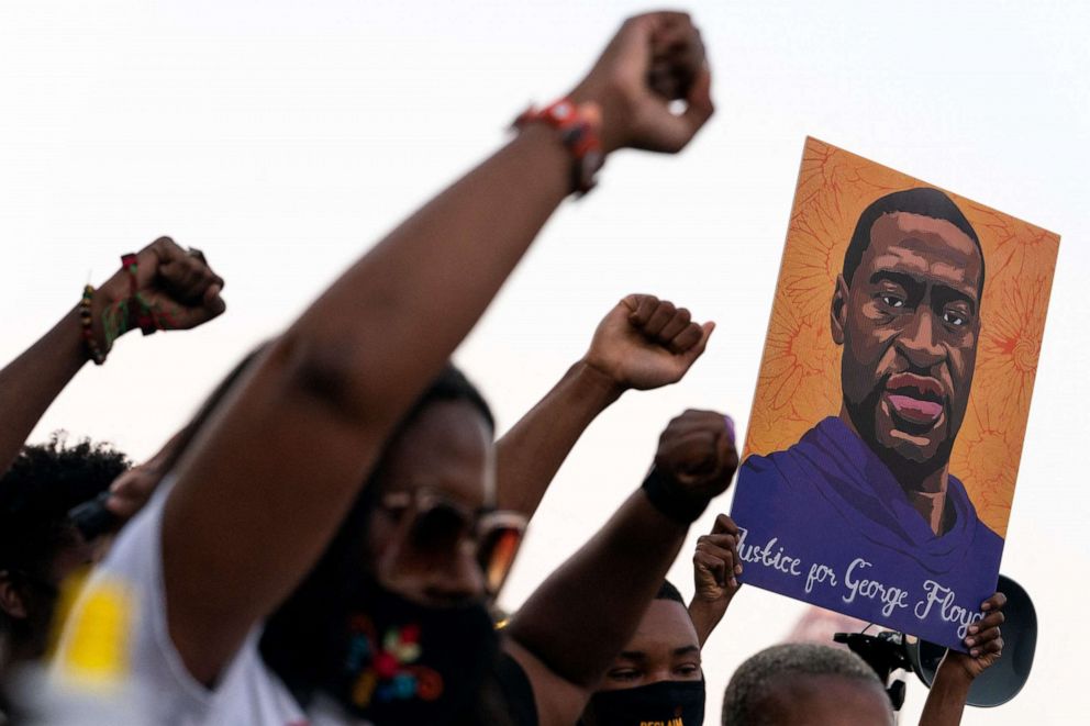 PHOTO: People raise their fists and hold a portrait of George Floyd during a rally following the guilty verdict the trial of Derek Chauvin, April 20, 2021, in Atlanta.