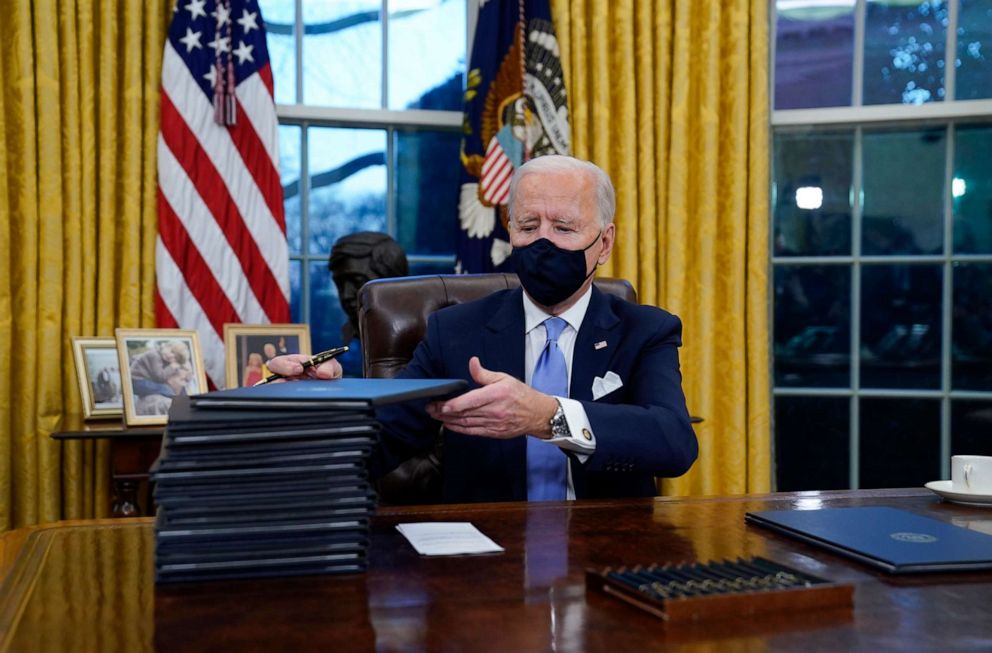 PHOTO: President Joe Biden signs his first executive orders in the Oval Office of the White House, Jan. 20, 2021. 