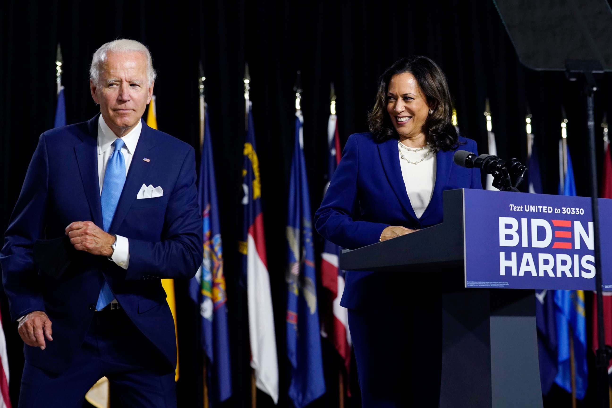 PHOTO: Democratic presidential candidate former Vice President Joe Biden retrieves his face mask from the podium before his running mate Sen. Kamala Harris speaks during a campaign event at Alexis Dupont High School in Wilmington, Del., Aug. 12, 2020.