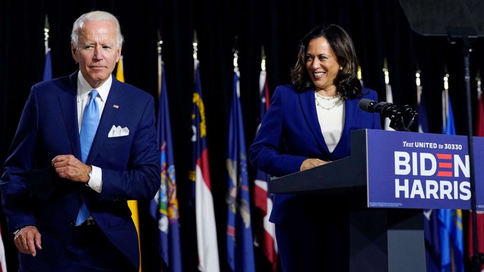 PHOTO: Democratic presidential candidate former Vice President Joe Biden retrieves his face mask from the podium before his running mate Sen. Kamala Harris speaks during a campaign event at Alexis Dupont High School in Wilmington, Del., Aug. 12, 2020.